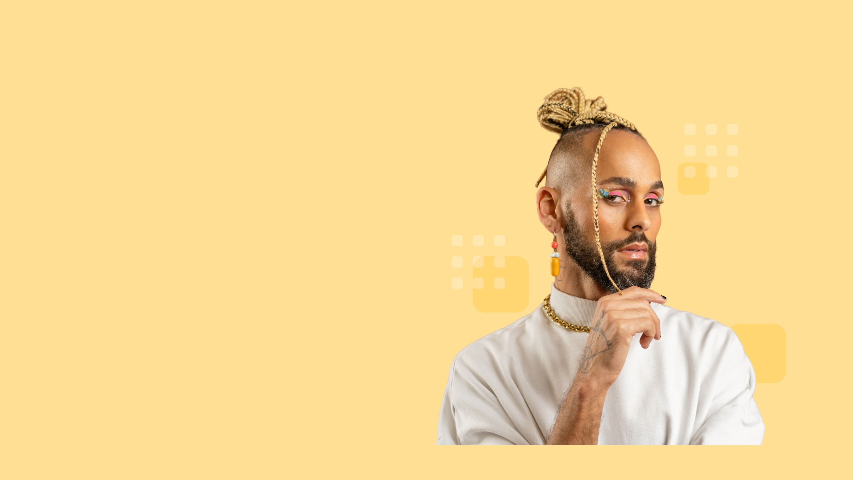 Confident individual with braided topknot, beard, colorful eye makeup, and wearing a white top.