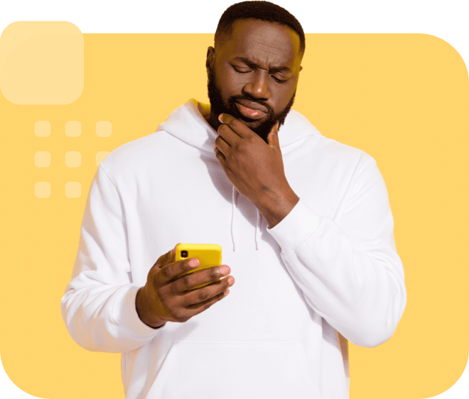 Individual in a white hoodie, holding a yellow smartphone, and looking at it thoughtfully.