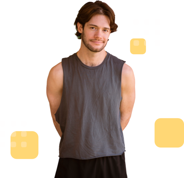 Smiling individual with medium-length hair, and wearing a sleeveless dark gray shirt, hands behind back.